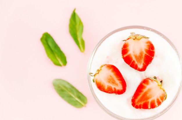 Fresas con yogur y hojas verdes.