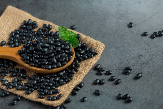 Frijol negro en una pequeña cuchara de madera colocada sobre tela de saco