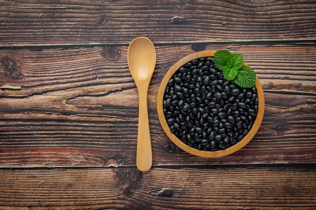 Frijol negro en un pequeño lugar de placa de madera sobre un piso de madera