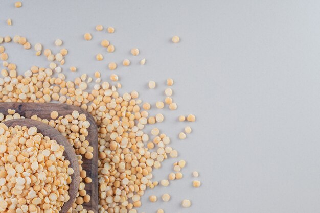 Frijoles amarillos en un plato de madera sobre hormigón.