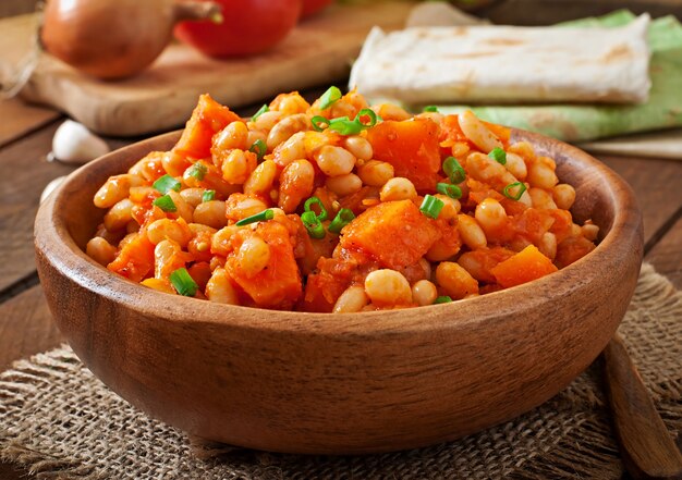 Frijoles blancos guisados y rodajas de calabaza en salsa de tomate