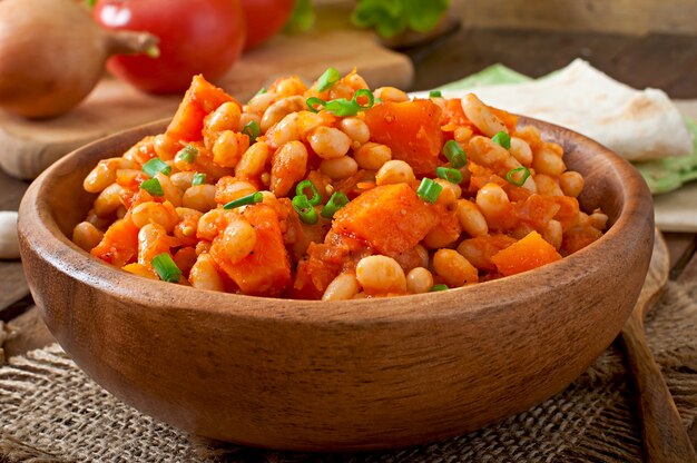 Frijoles blancos guisados y rodajas de calabaza en salsa de tomate