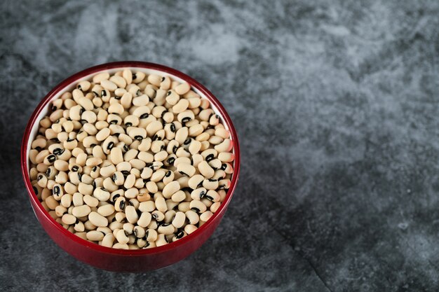 Frijoles blancos secos en un tazón rojo