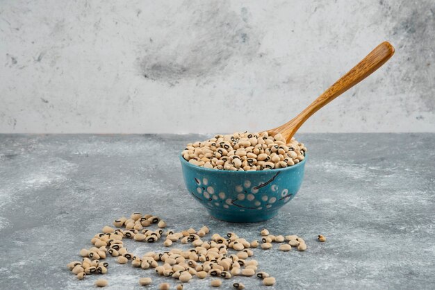 Frijoles blancos en un tazón azul con cuchara.