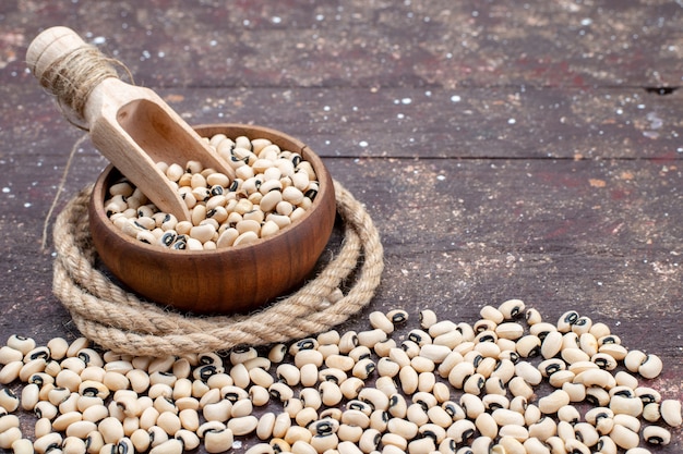 frijoles crudos frescos dentro de un tazón marrón y esparcidos por todo el marrón, comida frijol judía foto