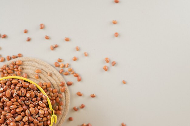 Frijoles marrones en un plato amarillo sobre hormigón.