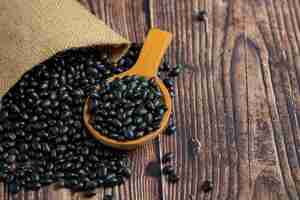 Foto gratuita frijoles negros en una pequeña cuchara de madera, coloque junto a la bolsa de saco llena de frijoles negros