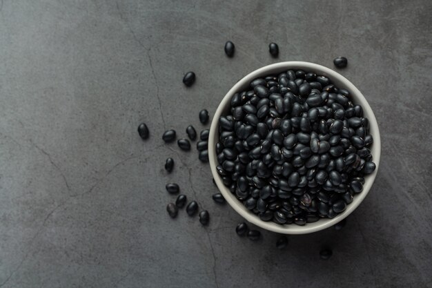 Frijoles negros en un tazón pequeño blanco en un lugar oscuro