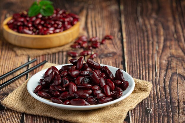 Frijoles rojos hervidos en placa blanca sobre un piso de madera