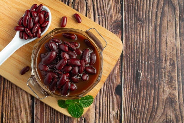 Frijoles rojos hervidos en un tazón de vidrio en lugar de la tabla de cortar de madera