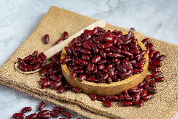 Frijoles rojos en un lugar de placa de madera pequeña sobre tela de saco