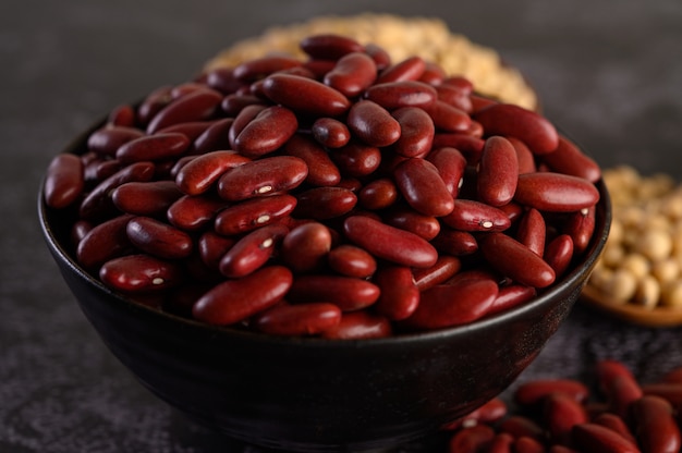 Frijoles rojos en un recipiente de madera en el piso de cemento negro.