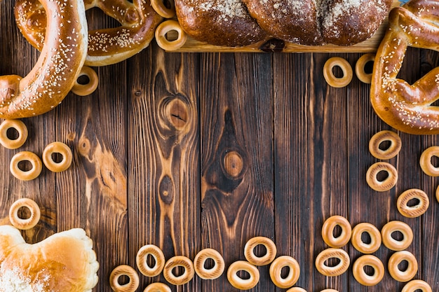 Frontera hecha con pan trenzado recién horneado, pretzels y panecillos en el fondo de madera