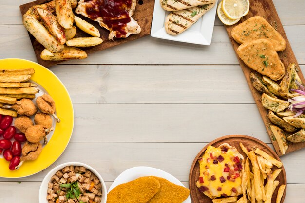 Frontera hecha de platos de pollo de comida rápida en mesa de madera