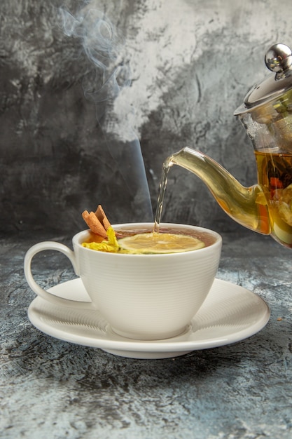 Frotn view hervidor con té vertido en una taza sobre la superficie oscura de la ceremonia del té por la mañana