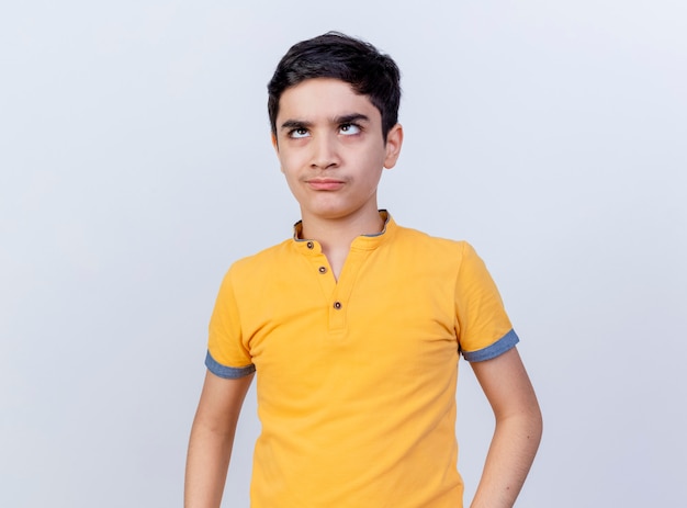 Foto gratuita fruncir el ceño joven caucásico cruzando los ojos mirando hacia arriba aislado sobre fondo blanco con espacio de copia