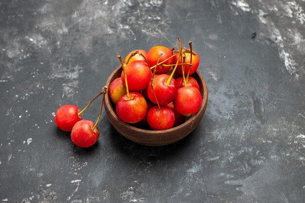 Fruta de cereza roja fresca en un recipiente marrón sobre fondo gris