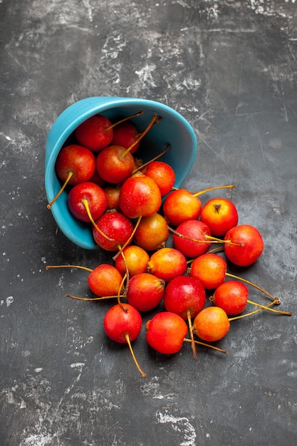 Fruta de cereza roja fresca en un recipiente sobre fondo gris