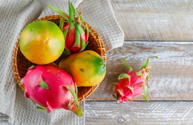 La fruta del dragón en una cesta de mimbre plana yacía sobre una toalla de madera y cocina