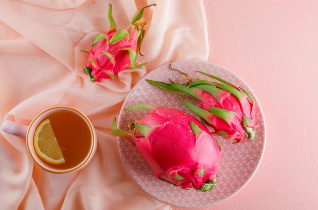 La fruta del dragón en un plato con té plano yacía sobre la mesa rosa