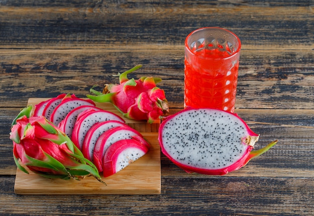 Fruta del dragón con vista de ángulo alto de jugo en tabla de cortar y madera