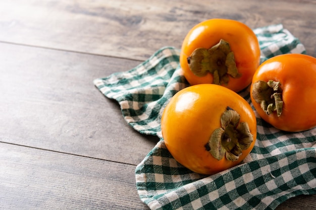 Foto gratuita fruta fresca de caqui en mesa de madera