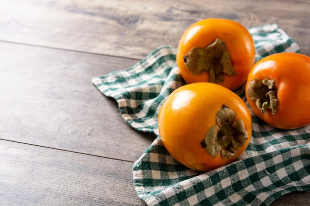 Fruta fresca de caqui en mesa de madera