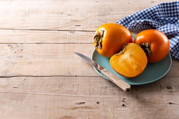 Fruta fresca de caqui en mesa de madera