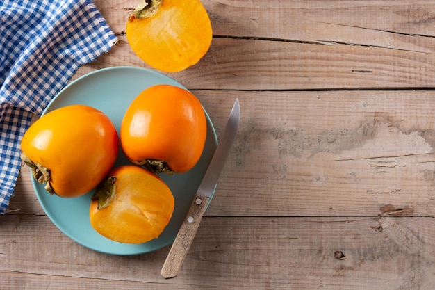 Fruta fresca de caqui en mesa de madera