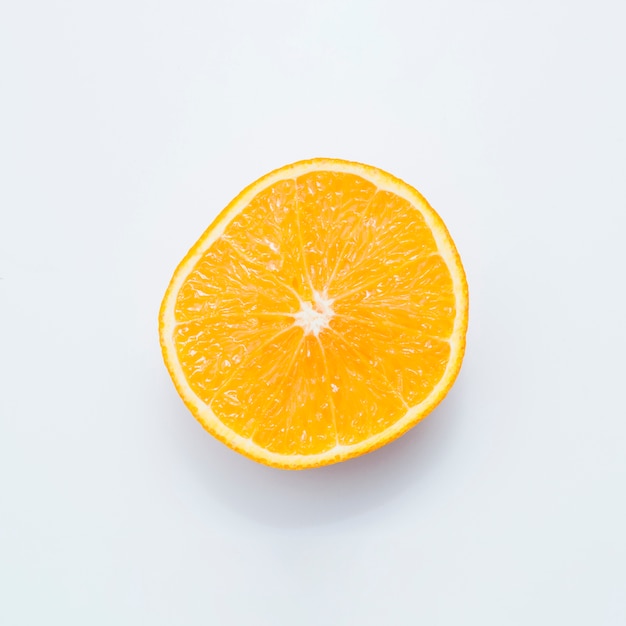 Fruta jugosa anaranjada partida en dos aislada en el fondo blanco