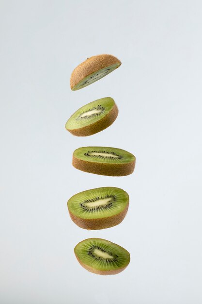 Fruta de kiwi en rodajas flotantes con fondo claro