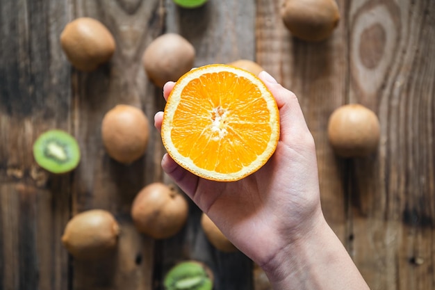 Foto gratuita fruta naranja en manos femeninas en una vista superior de fondo de madera borrosa