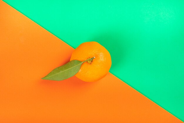 Fruta naranja sobre superficie colorida naranja y verde