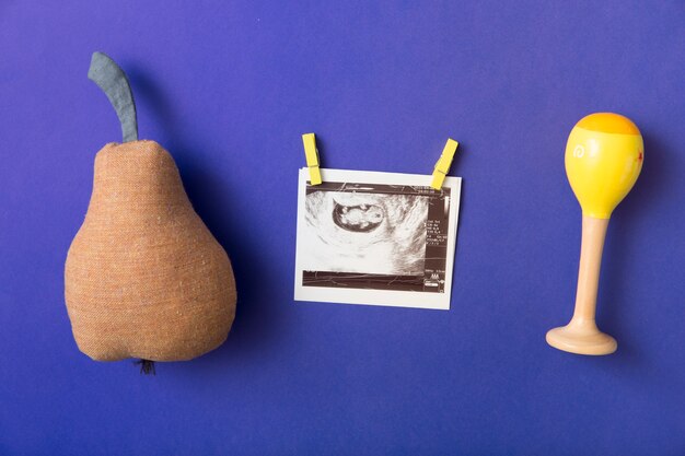 Fruta de pera rellena; Sonajero y pinza para la ropa con imagen de ultrasonido sobre fondo de color azul