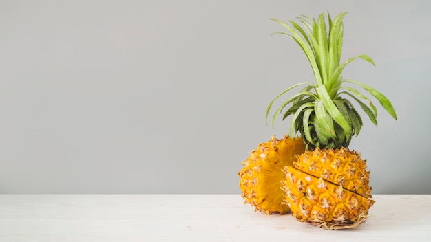 Fruta de piña en rodajas frente a la pared gris