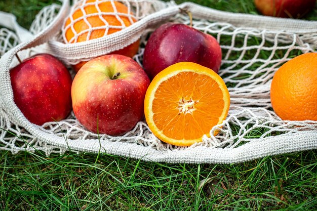 Frutas brillantes en una bolsa de hilo blanco en la hierba