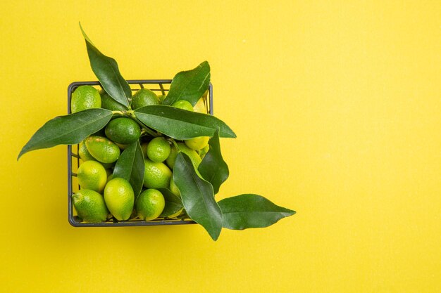 Frutas en canasta canasta de frutas cítricas verdes con hojas sobre la mesa