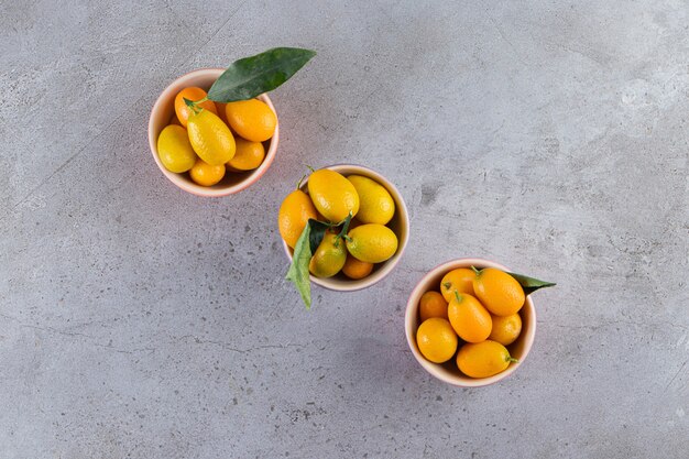 Frutas cítricas frescas cumquat con hojas colocadas en un tazón.