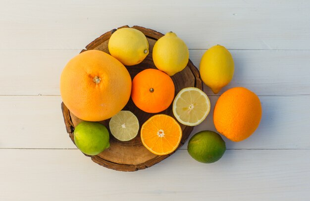 Frutas cítricas en tabla de cortar y fondo de madera. endecha plana.