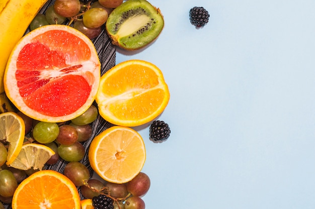 Frutas cítricas; Uvas y moras sobre fondo azul