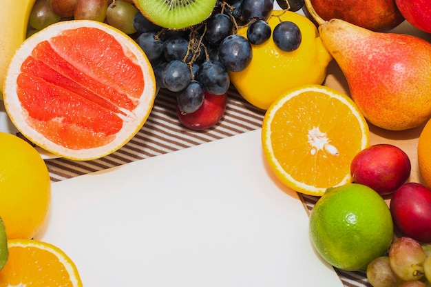 Frutas cítricas; uvas; peras; limón; con papel blanco en blanco