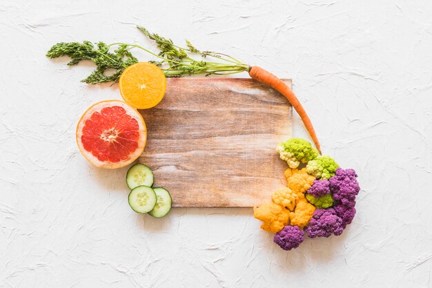 Frutas y coliflor en bloque de madera sobre fondo blanco de textura