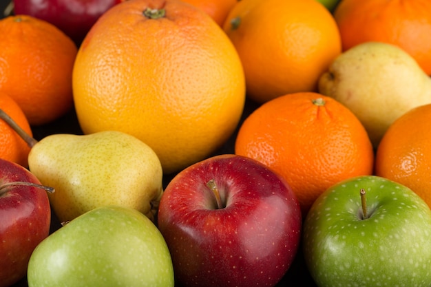 Frutas coloridas montón de diferentes frutas como manzanas y naranjas en escritorio gris