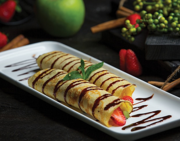 Frutas envueltas en crepes y salsa de chocolate.