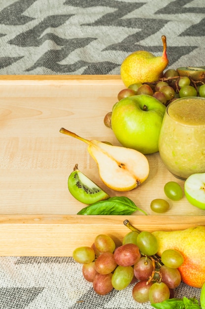 Frutas frescas en bandeja de madera contra mantel