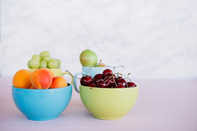 Frutas frescas saludables en un recipiente en la superficie blanca