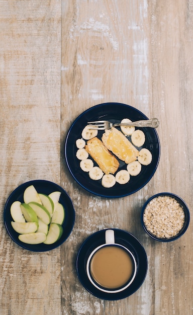 Frutas frescas saludables; Taza de muesli y café sobre fondo de madera con textura