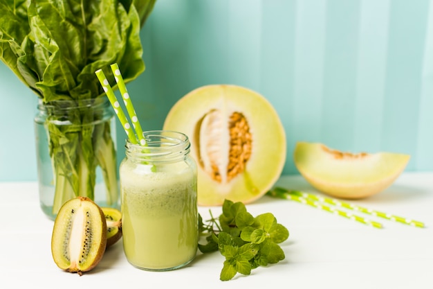 Frutas junto a hierbas y copa con cóctel.