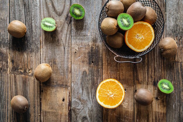 Foto gratuita frutas de kiwi y naranja en una vista superior de fondo de madera