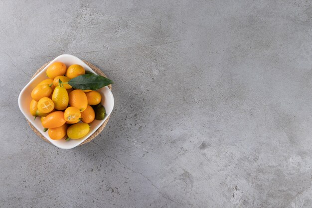 Frutas Kumquat en un cuenco, sobre la mesa de mármol.